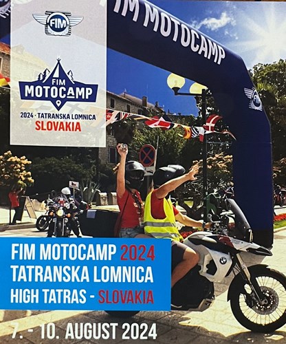 Bilden visar information om ett evenemang kallat "FIM MOTOCAMP". Huvudinformationen på bilden är:  Evenemanget heter "FIM MOTOCAMP". Det kommer att äga rum i "Tatranska Lomnica" i Slovakien. Datumet för evenemanget är från den 7:e till den 10:e augusti 2024. I bakgrunden av bilden ses en stor blå båge med texten "FIM MOTOCAMP" och FIM:s logotyp. Under bågen finns flera flaggor från olika länder hängande. Det finns också en person som sitter på en motorcykel och en annan person stående bredvid. Båda bär hjälmar, och den stående personen har en gul väst. Bakom dem finns byggnader och träd.  Den nedre delen av bilden har en blå ruta med vit text som anger evenemangets namn, plats och datum.  Överlag ger bilden intrycket av ett internationellt motorcykelevenemang med deltagare från olika länder. Atmosfären verkar festlig och välkomnande.